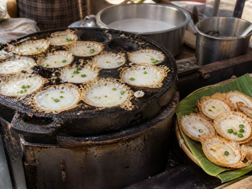Traditional Thai khanom khrok coconut rice pancakes cooking over market heat