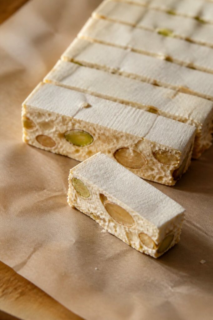 Miel, amandes et pistaches dans un nougat tendre découpé
