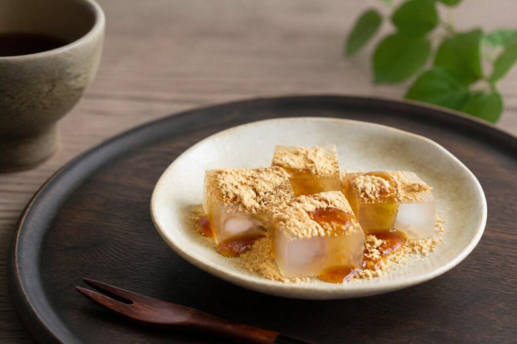 A tea cup accompanies kuzumochi coated with brown syrup